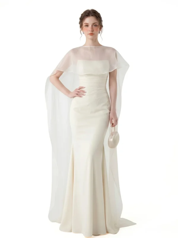 Model trägt ein trägerloses Satin-Meerjungfrauenkleid in Elfenbein mit transparentem, fließendem Cape.